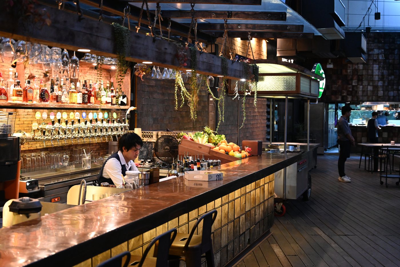 The bar, backlit bottles along a long wooden counter